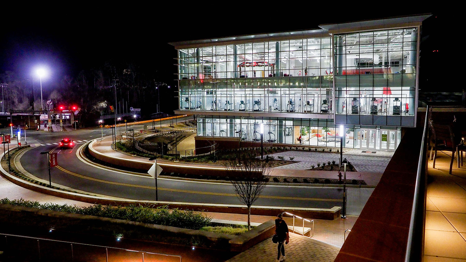 An exterior view of the Wellness and Recreation Center at night, with large windows showing off the state-of-the-art equipment inside.